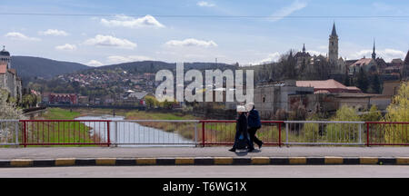 SIGHISOARA, Roumanie - le 9 avril 2019 : trois vieilles dames marche sur le pont sur la rivière Tarnava à Sighisoara. Plan large avec vue sur les tours o Banque D'Images