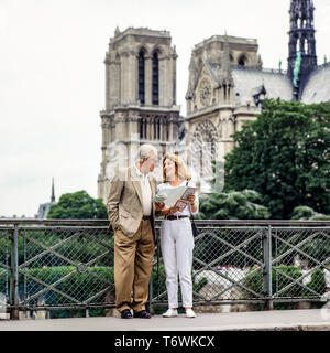 Couple de touristes d'âge moyen à la recherche au plan de la ville en face de la cathédrale Notre-Dame de Paris, avant l'incendie du 15 avril 2019, Paris, France, Europe, Banque D'Images