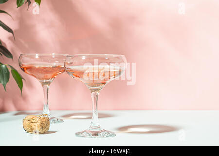 Champagne ou de vin dans l'élégant quartier de verres sur un fond rose lumière vive. Copier l'espace. Focus sélectif. Banque D'Images