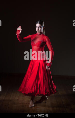 Belle jeune danseuse de flamenco hispanique en robe rouge isolé sur fond noir Banque D'Images