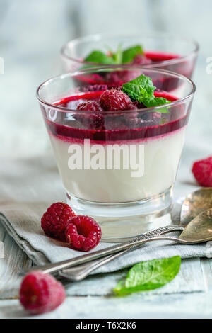 Panacotta vanille avec sauce aux framboises et menthe. Banque D'Images