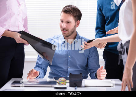 Young Businessman Looking At Document affiché par le partenaire Banque D'Images