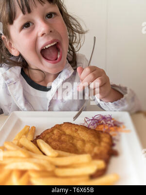 Peu d'Italien girl eating viande panées et frites Banque D'Images