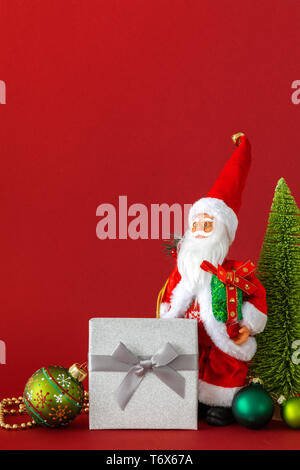 La figure du Père Noël boîte-cadeau en argent et fond rouge Banque D'Images