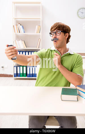 Étudiant avec fake moustache reading book Banque D'Images