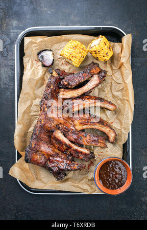 Côtes levées barbecue St Louis coupe avec marinade Piment chaud au miel et le maïs comme vue de dessus dans une poêle Banque D'Images