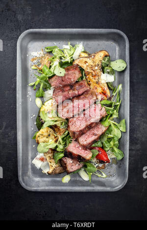 Style moderne italien tagliata di manzo avec salade d'agneau rôti de boeuf en tranches d'âge à sec en vue de dessus dans une poêle Banque D'Images