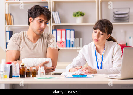 Jeune homme au bras bandé visiter médecin femme traumatologis Banque D'Images