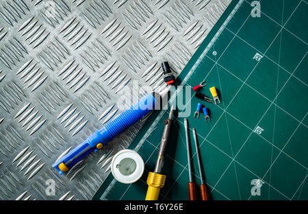 Outils de soudage. Fer à souder, tiroir de fil de brasure, tournevis, cosses isolées sans soudure mis sur des groupes metal checker plate et Banque D'Images