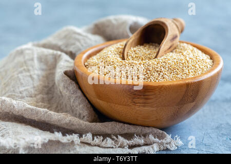 Le quinoa brut et d'un scoop dans un bol en bois. Banque D'Images
