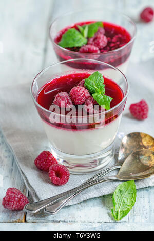 Panacotta vanille avec sauce aux framboises et menthe. Banque D'Images