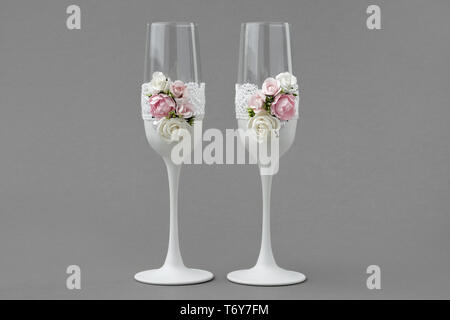 Deux verres à vin de mariage décoré de dentelles et roses sur fond gris. Banque D'Images