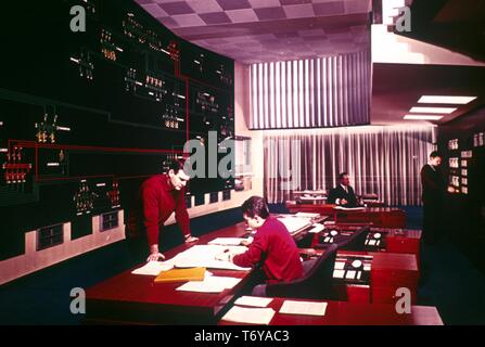 Quatre hommes se lever et s'asseoir à un bureau tout en travaillant dans une centrale nucléaire, salle de contrôle, 1975. Image courtoisie du département américain de l'énergie. () Banque D'Images