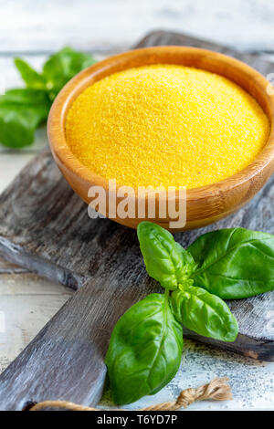 La polenta italienne non cuits dans un bol en bois. Banque D'Images