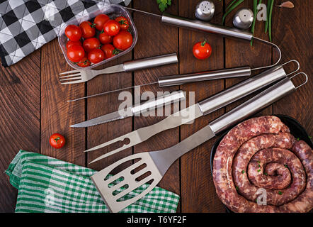 Outils et des saucisses barbecue sur table en bois. Mise à plat, vue du dessus Banque D'Images