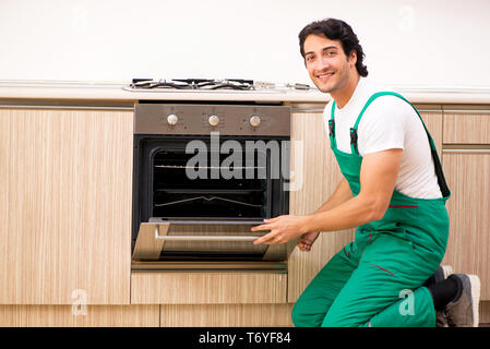 Jeune entrepreneur la réparation de four dans la cuisine Banque D'Images