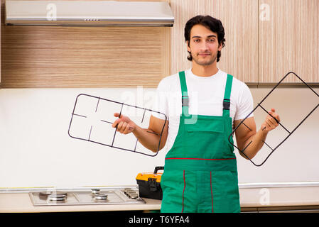 Jeune entrepreneur la réparation de four dans la cuisine Banque D'Images