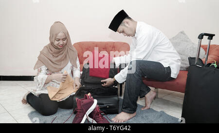 Heureux couple musulman homme et femme mettre ses affaires dans la valise avec une assurance préparer voyagent pour le ramadan moubarak eid celebration -droit Banque D'Images