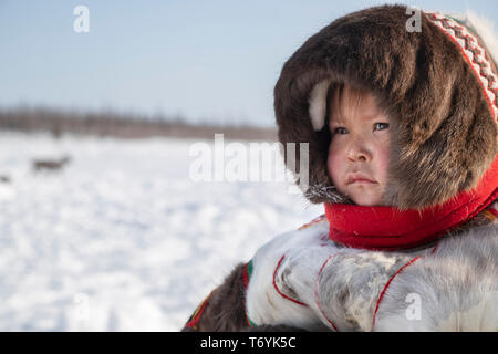 La Russie, dans la région autonome de Yamal-Nenets, péninsule de Yamal. Camp de nomades éleveurs de rennes Nenets, jeune enfant en tenue traditionnelle de fourrure de renne. Banque D'Images