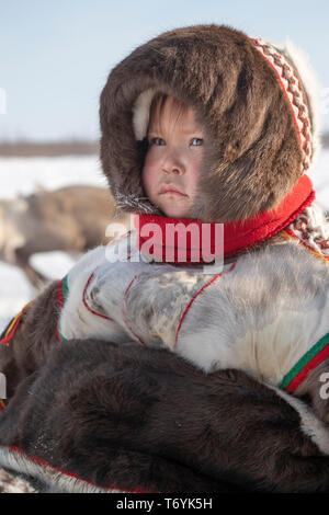 La Russie, dans la région autonome de Yamal-Nenets, péninsule de Yamal. Camp de nomades éleveurs de rennes Nenets, jeune enfant en tenue traditionnelle de fourrure de renne. Banque D'Images