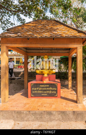 Sihanoukville, Cambodge - Mars 15, 2019 : Phsar Leu école élémentaire. Statue en or de gourou bouddhiste sous l'auvent. Les feuilles vertes à l'arrière. Banque D'Images