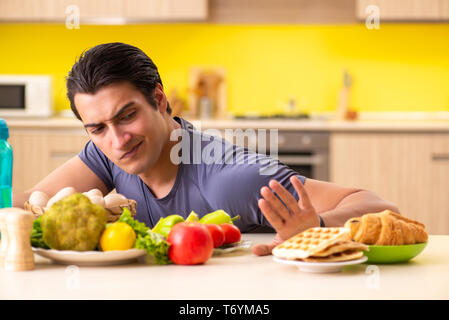 Homme avoir choix difficile entre les aliments sains et malsains Banque D'Images