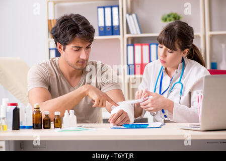 Le jeune homme au bras bandé visiter médecin femme traumatologist Banque D'Images