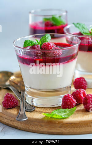 Panacotta vanille avec sauce aux framboises et menthe. Banque D'Images