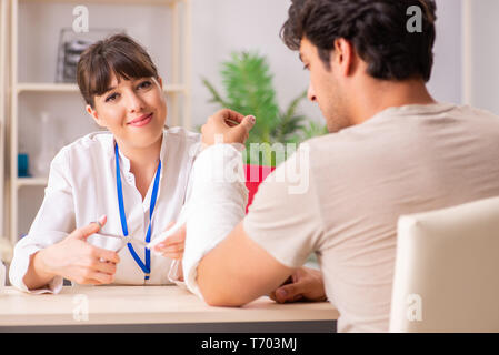 Jeune homme au bras bandé visiter médecin femme traumatologis Banque D'Images