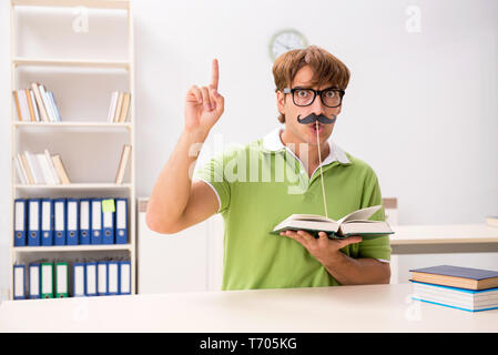 Étudiant avec fake moustache reading book Banque D'Images