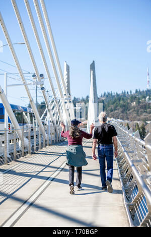 Un couple de personnes âgées un homme et femme en prenant soin de leur santé se promener sur le pont de passage Tilikum préférant une vie active portant un cha Banque D'Images