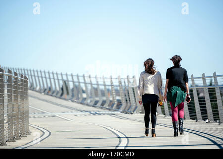 Deux jeunes filles parlent avec animation tout en marchant le long de Tilikum Crossing bridge combinant les conversations agréables les uns avec les autres avec exercice utile dans la marche Banque D'Images