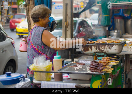 BANGKOK, THAÏLANDE - 27 décembre 2018 : femme frites brochettes de viande sur une rue de la ville. Bangkok Street Food Banque D'Images