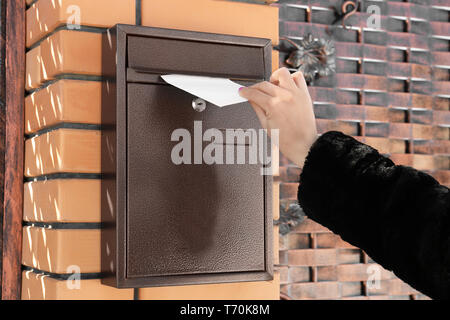 Woman putting lettre dans la boîte aux lettres à l'extérieur Banque D'Images