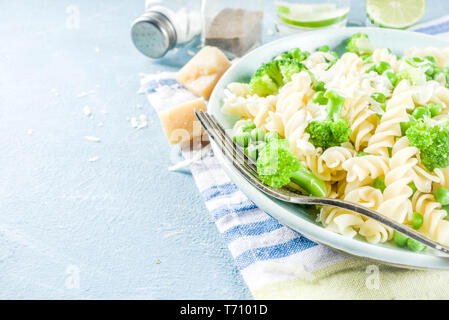 Pâtes aux légumes verts et parmesan. Salade de pâtes fusilli vegan avec le brocoli et les pois verts, bleu clair sur l'ardoise, de la pierre ou du béton zone Banque D'Images