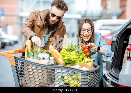 Les jeunes et l'heureux couple avec panier rempli d'aliments frais et sains à l'extérieur Banque D'Images