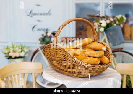 Le panier de paille avec un grand nombre de petites baguettes est sur une table avec une nappe blanche Banque D'Images