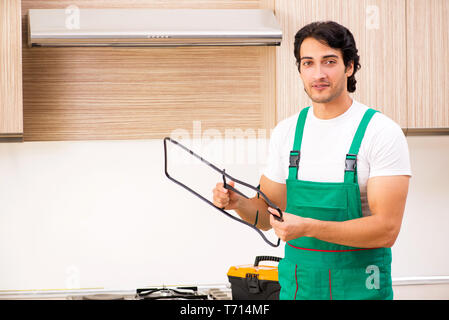 Jeune entrepreneur la réparation de four dans la cuisine Banque D'Images