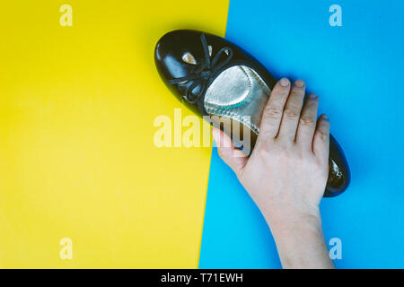 Woman hand holding chaussures noires sur fond coloré Banque D'Images