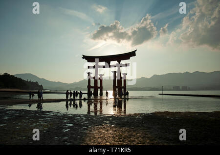 Les gens qui se profile au crépuscule à côté de la gigantesque torii flottant d'Itsukushima, île de Miyajima, dans l'ouest de Honshu, Japon, Asie Banque D'Images