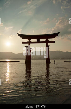 Les gens qui se profile au crépuscule à côté de la gigantesque torii flottant d'Itsukushima, île de Miyajima, dans l'ouest de Honshu, Japon, Asie Banque D'Images