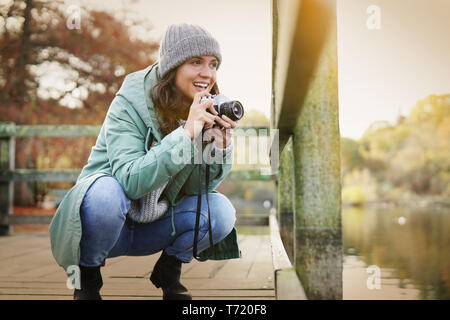 Jolie jeune femme brune en prenant des photos en plein air à l'automne Banque D'Images