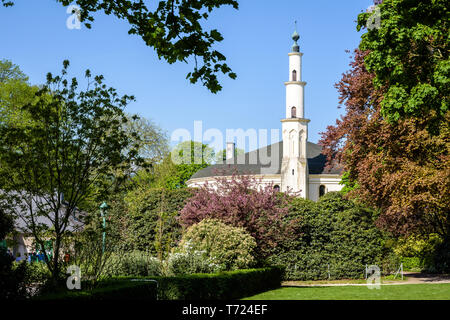 Le minaret de la grande mosquée de Bruxelles, Belgique, dépassant au-dessus des buissons dans le Parc du Cinquantenaire au printemps. Banque D'Images