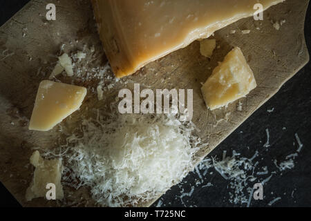 Fromage parmesan râpé sur fond noir, la cuisine italienne. Les aliments sombres Banque D'Images