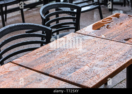Piscine wet tables et chaises en bois sous la pluie Banque D'Images