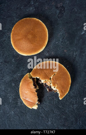 Portrait de deux dorayaki, une pâtisserie remplie de pâte de haricots adzuki typique de Japon, sur une surface de pierre noire élégante Banque D'Images