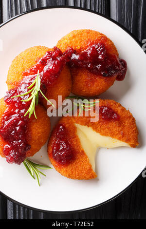 Soft délicate dans le Camembert de la panure servi avec sauce aux canneberges et romarin gros plan sur une assiette sur la table. Haut Vertical Vue de dessus Banque D'Images