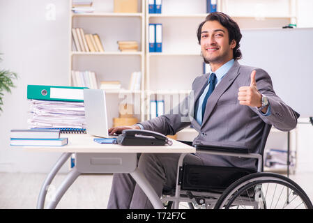 Beau jeune employé en fauteuil roulant à l'office de tourisme Banque D'Images