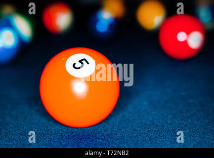 Gros plan macro de l'orange vif 5 Ball Pool balls multicolores avec en arrière-plan sur la table de billard feutré teal Banque D'Images
