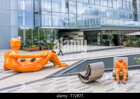 Imitant la vie art - un ouvrier s'arrête pour le déjeuner à côté de gens du chant par Jesse Vin à Battersea Power Station, Londres. Banque D'Images